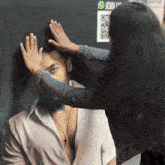 a woman touches a man 's head in front of a wall that says join us