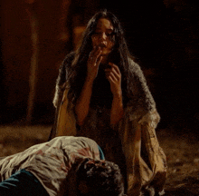 a woman is kneeling down next to a man who is laying on the ground