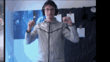 a man wearing headphones and a nike jacket stands in front of a blue wall .