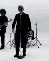 a man singing into a microphone while a man plays a bass guitar