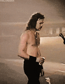 a man without a shirt is standing in front of a microphone with the words " thelordera " on the bottom left