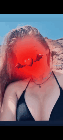 a woman wearing a black bikini has a red bat on her face