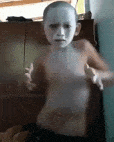 a young boy with white paint on his face is dancing in a room .