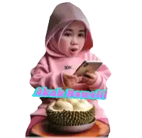 a girl in a pink hoodie is holding a cell phone in front of a durian