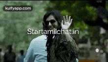 a woman wearing sunglasses is waving her hand in front of a sign that says starttamilchat.in