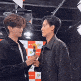 two men are standing next to each other and one of them is holding a yellow flower
