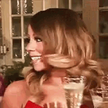 a woman in a red dress is smiling while holding a glass of champagne .