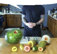 a man in a black shirt is standing in a kitchen surrounded by fruits