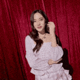 a woman standing in front of a red curtain wearing a plaid top and skirt