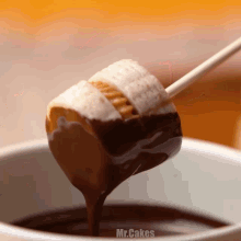 a marshmallow is being dipped into a chocolate fondue
