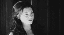 a black and white photo of a woman 's face with a man in the background .