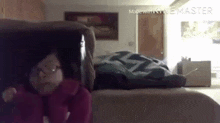 a person is sitting on a couch in a room with a blanket on the bed .