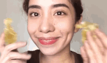 a close up of a woman 's face with a smile on her face while holding a lemon .