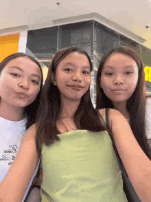 three girls are posing for a picture with one wearing a shirt that says ' guess '