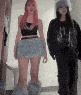 a girl with pink hair is wearing a black tank top and a blue skirt
