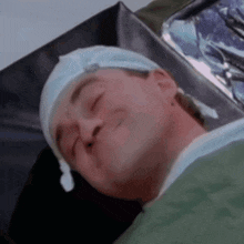 a man laying in a hospital bed with his eyes closed and a hat on his head