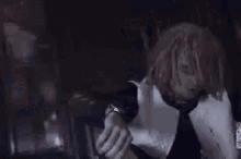 a man with dreadlocks is making a gun gesture with his hands in the dark .
