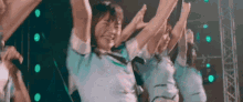 a group of girls are dancing on stage with their arms in the air .