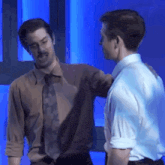 two men are standing next to each other on a stage and hugging each other .