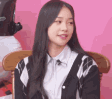 a girl with long black hair is sitting in a chair with a microphone attached to her neck