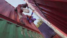 a man in a superhero costume is falling off a shipping container that says eitudies