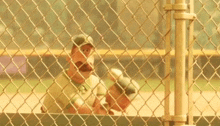 two baseball players behind a chain link fence