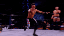 a wrestler is doing a flip in a wrestling ring while another wrestler looks on .