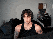a man with tattoos is wearing headphones and looking at a computer screen .