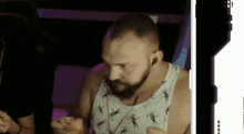 a man with a beard wearing a white tank top with scissors on it
