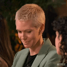 a woman with short blonde hair is smiling while sitting next to another woman .