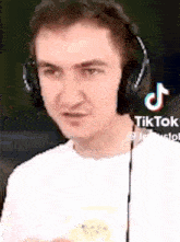 a man wearing headphones and a white shirt is looking at the camera .