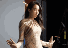 a woman in a striped dress stands with her hands outstretched
