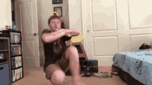 a man squatting in a room with a bed and a shelf full of books