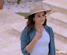 a woman wearing a hat and a blue shirt has a watermark that says imgplay on the bottom right