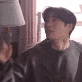 a man is sitting on a couch in front of a lamp in a room .