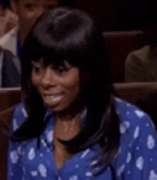 a woman in a blue shirt is smiling while sitting in a theater .