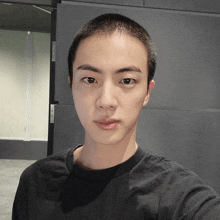 a man with a shaved head is wearing a black t-shirt