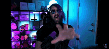 a man with purple hair and sunglasses is making a funny face in front of a sign that says welcome home roommate