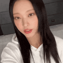 a woman wearing a white hoodie is taking a selfie
