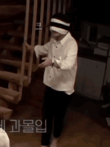 a man in a white shirt and black pants is standing next to a staircase .