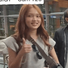 a woman is giving a thumbs up and smiling
