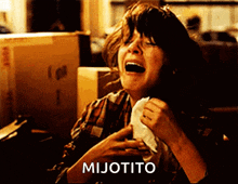 a woman is crying and holding a napkin in front of a box that says mijorito