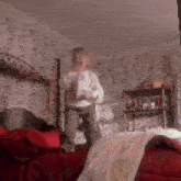 a person is standing on a bed in a room holding a remote control .