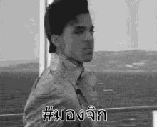 a black and white photo of a man standing in front of a window with foreign writing on it .