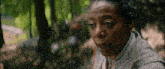a close up of a woman 's face in the woods with trees in the background