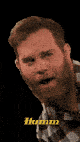 a man with a beard is making a funny face and the word humm is on the bottom right