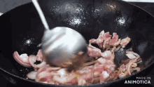 a pan of food is being stirred with a spoon and the words made in animotica are visible in the corner