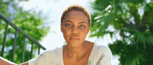 a woman with short hair is sitting on a railing looking at the camera .