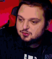a man with a beard is sitting in a chair and making a face .