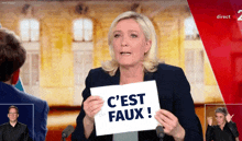 a woman is holding a sign that says c est faux